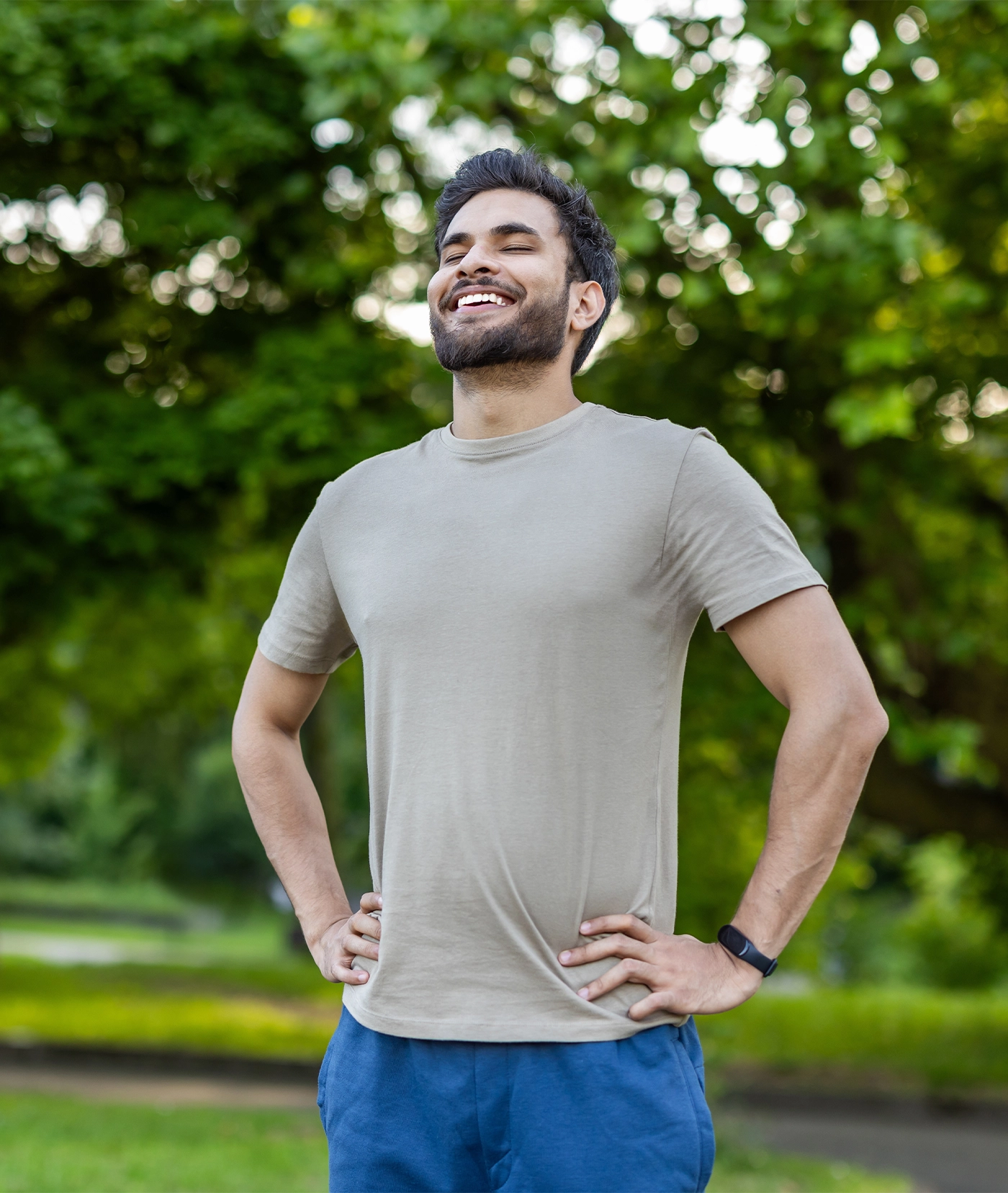 smiling joyfully in lush green park after physical exercise. Display of contentment and relaxation in outdoor environment