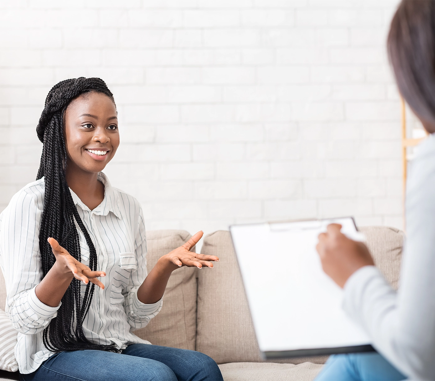 Successful therapy. Happy black female patient talking to psychologist at her office, expressing gratitude
