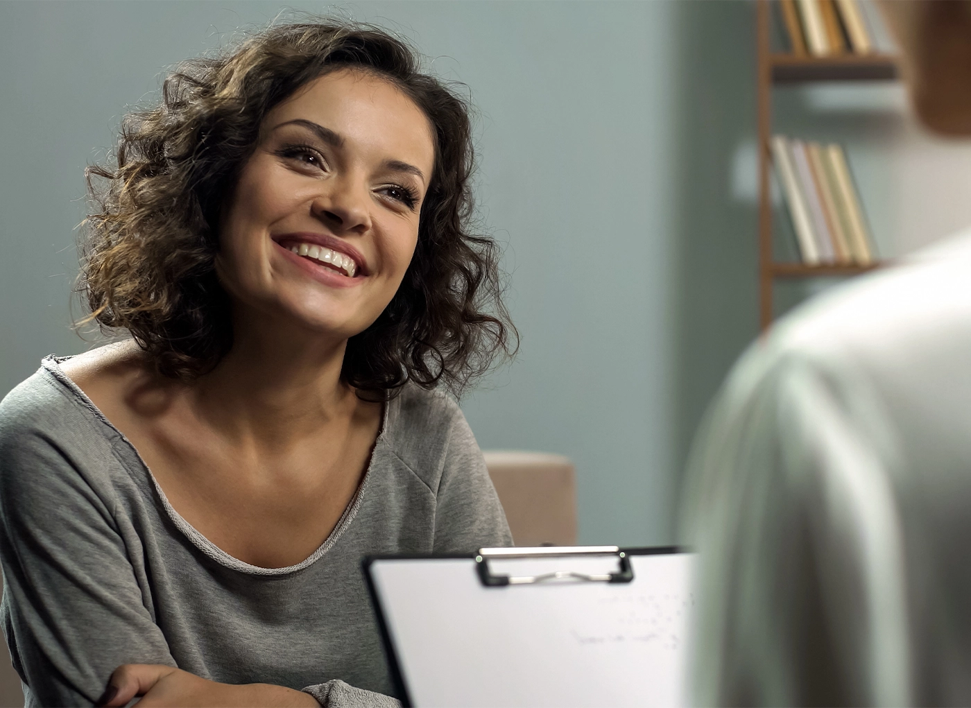 Young happy lady talking with psychologist at clinic, session of rehab therapy