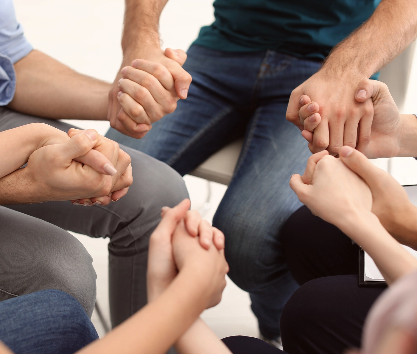 People holding hands together at group therapy session