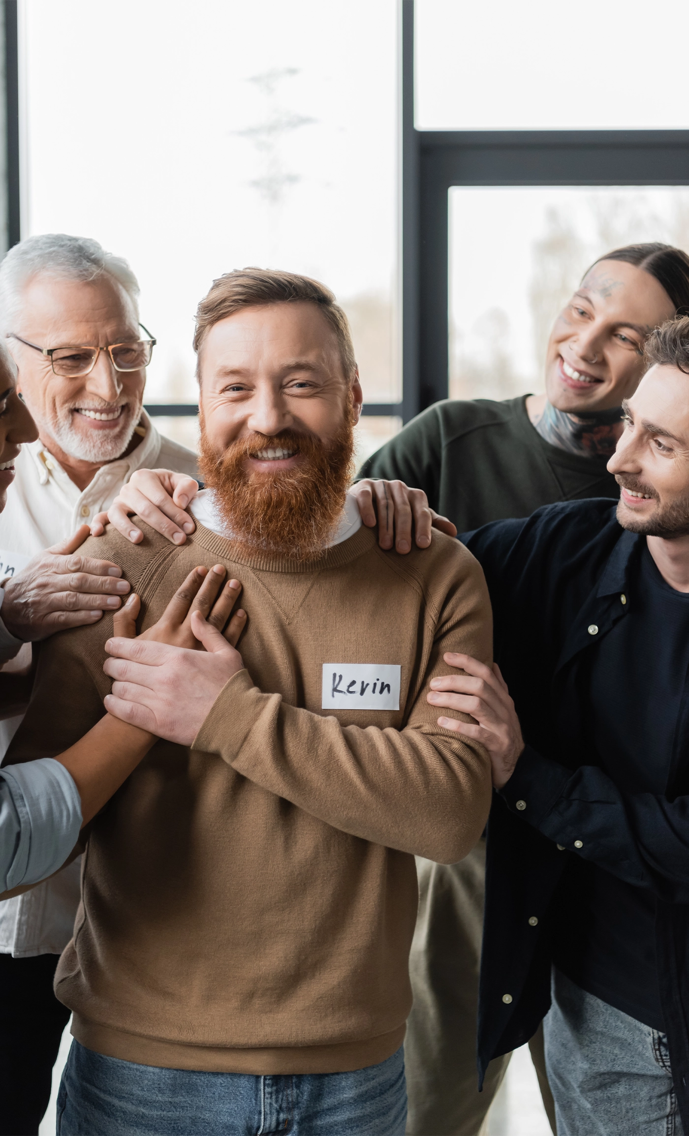 positive multiethnic people hugging man in rehab center