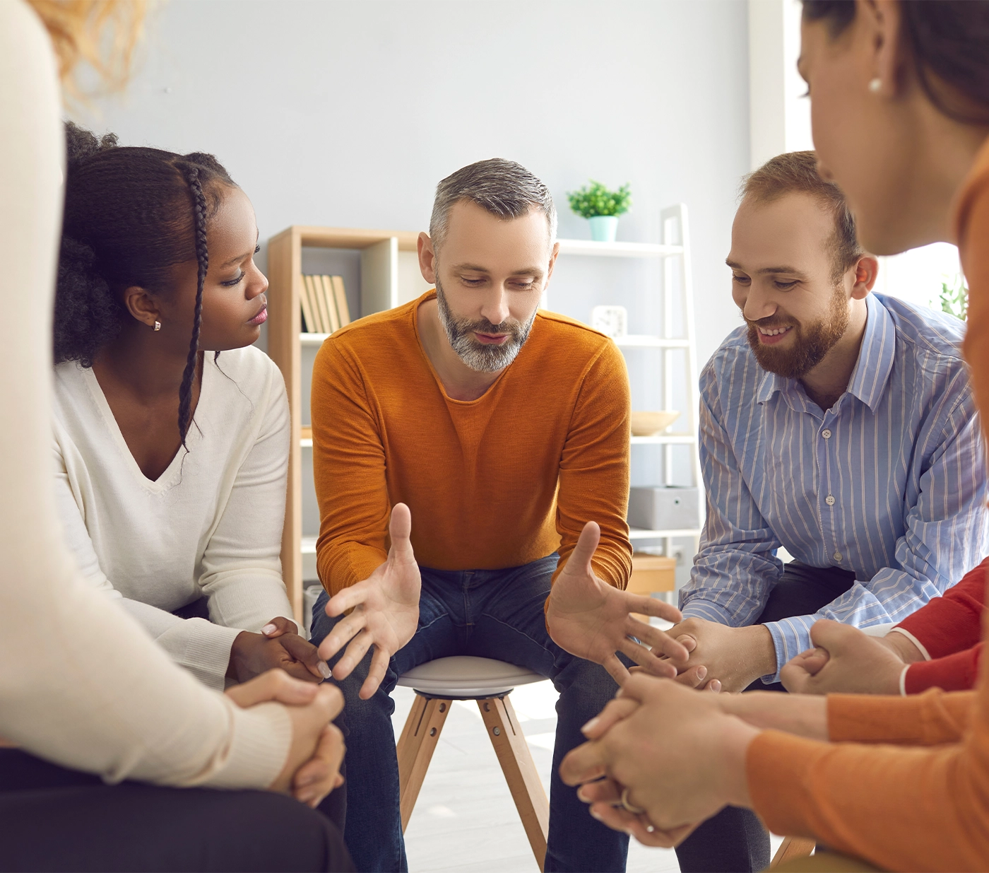 Professional experienced therapist talking to diverse patients during group therapy session