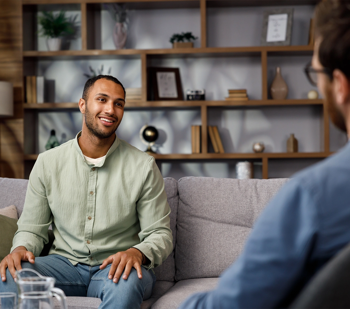 Visiting a psychologist A man sits on a couch and talks to a psychotherapist. He thanks the doctor and smiles, therapy helped him. Help of a psychologist.