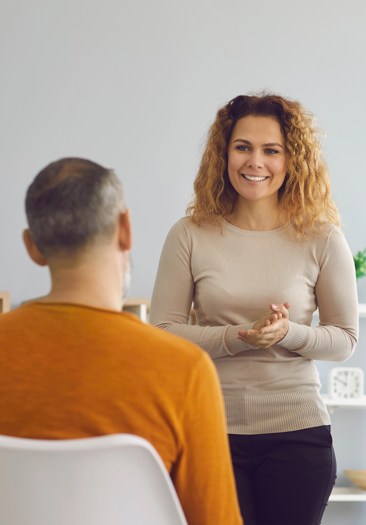 Happy beautiful woman making presentation standing in front of diverse audience. Psychologist or coach talking to group of young and mature people. Team of company workers listening to female speaker