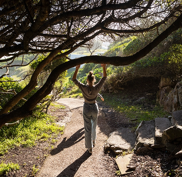 Teenage girl walking along a path on a nature trail, under overhanging trees.