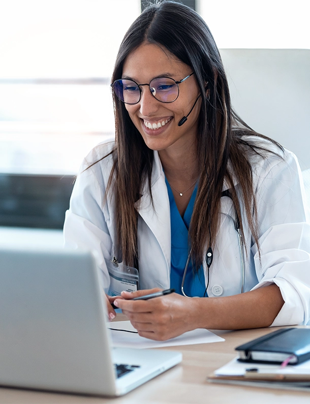 Shot of female doctor talking with patient through a video call with a laptop in the consultation.