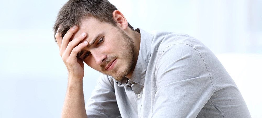 Sad worried man complaining sitting alone on a couch at home