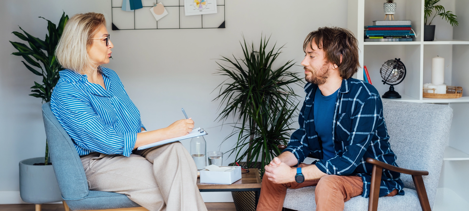 Depressed male patient having psychotherapy session with counselor at mental health clinic. Man with emotional problems consulting professional therapist i comfy office. Psychological help service.