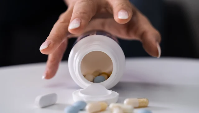 Drug Addicted Woman Reaching For Medication At Home