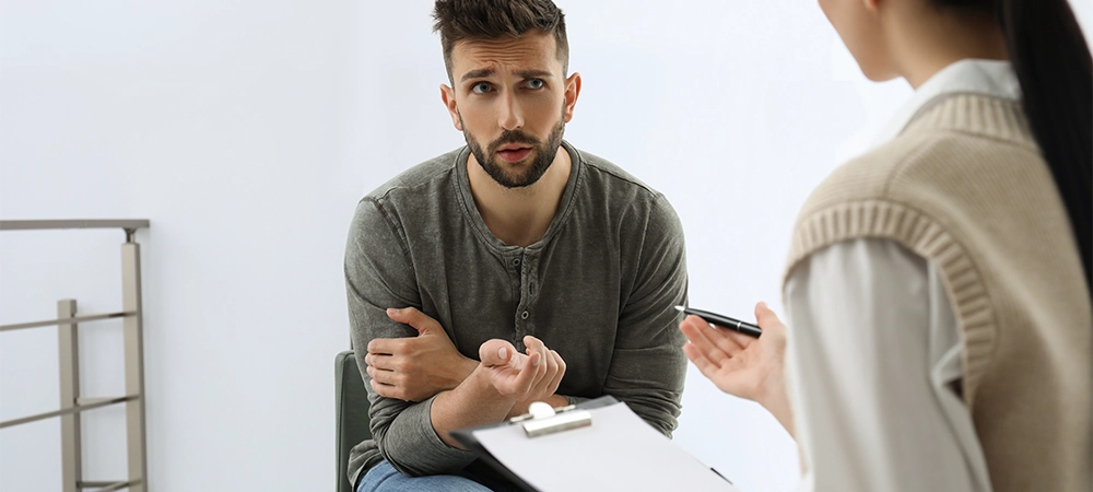 Psychotherapist working with drug addicted man indoors