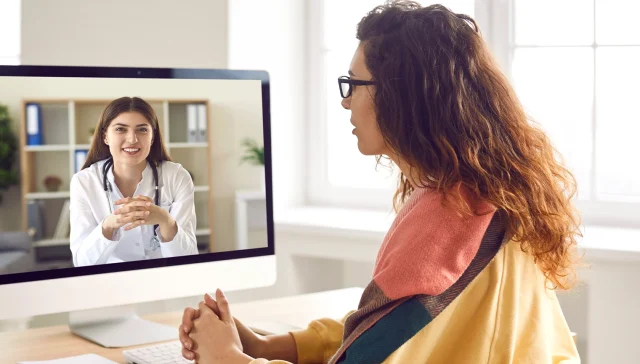 Sick woman listening recommendations and appointment having online video call with a female friendly smiling doctor using pc computer at home. Telemedicine and patient consultation online concept.