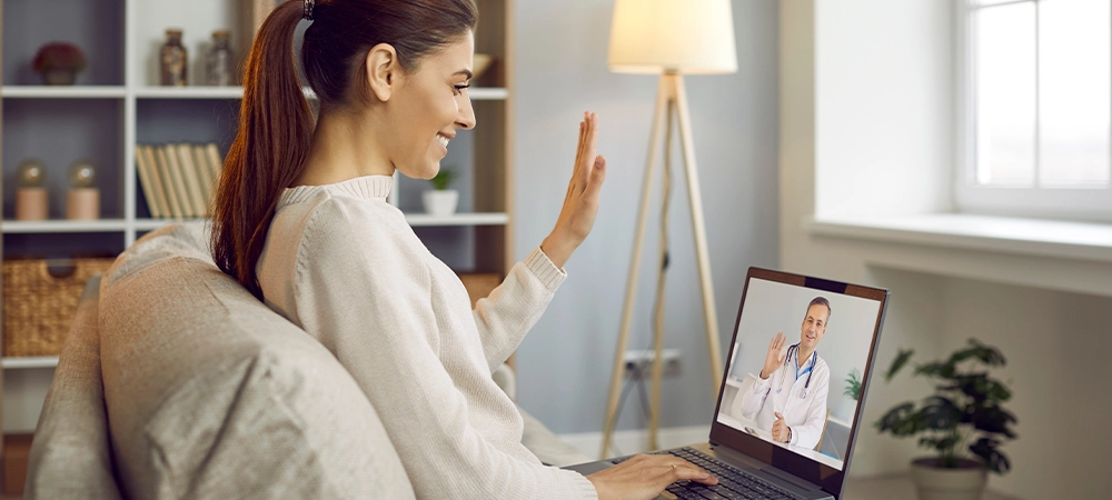Smiling woman talk on video call with doctor on lockdown at home. Happy female patient have webcam virtual conversation with GP on computer. Distant consultation with medical specialist.