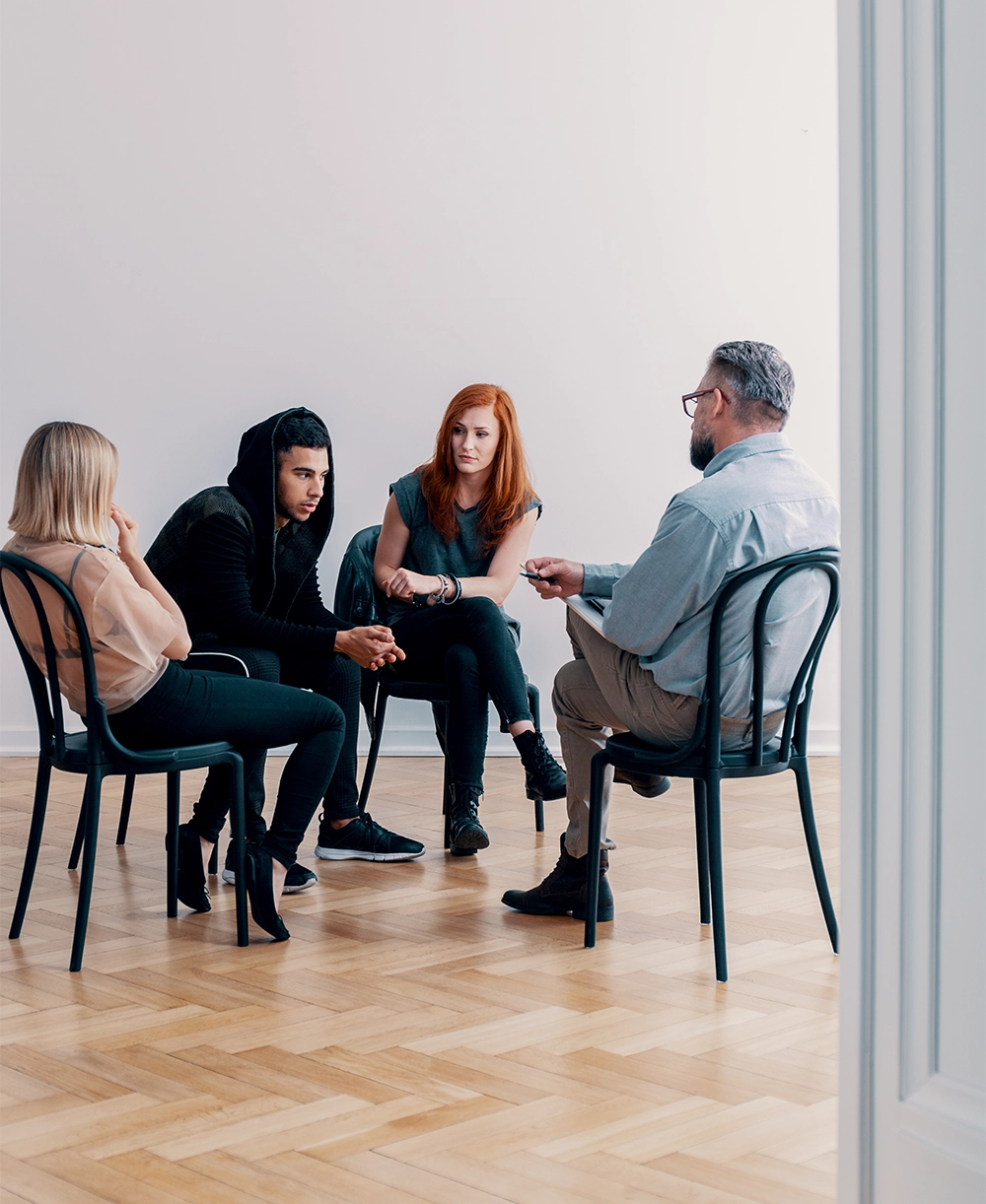 Group of rebellious teenagers talking to a psychologist in a rehab facility