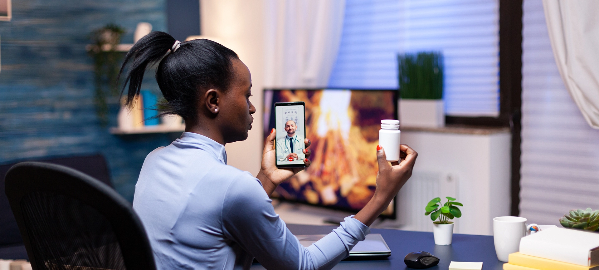 Dark skinned woman showing pills bottle to doctor during video call late at night from living room. Black patient in a video call with medic discussing health problems of woman.